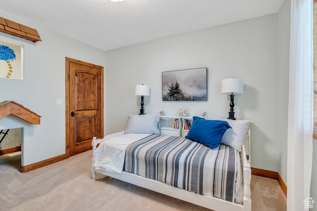 Bedroom featuring carpet flooring, baseboards, and a textured ceiling