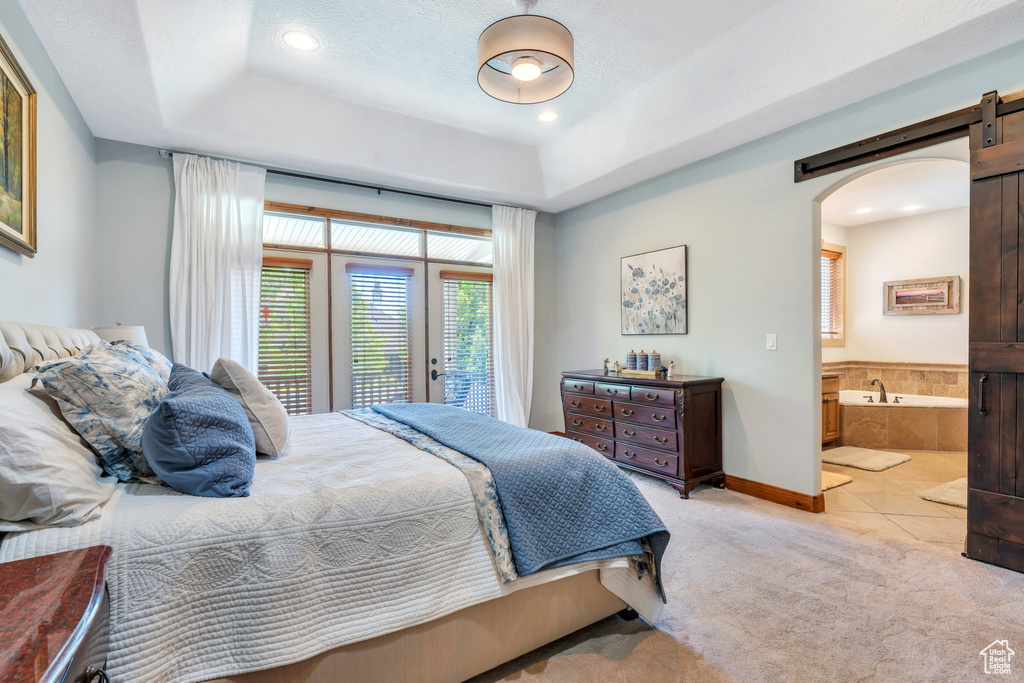 Bedroom with a raised ceiling, arched walkways, light colored carpet, access to outside, and recessed lighting