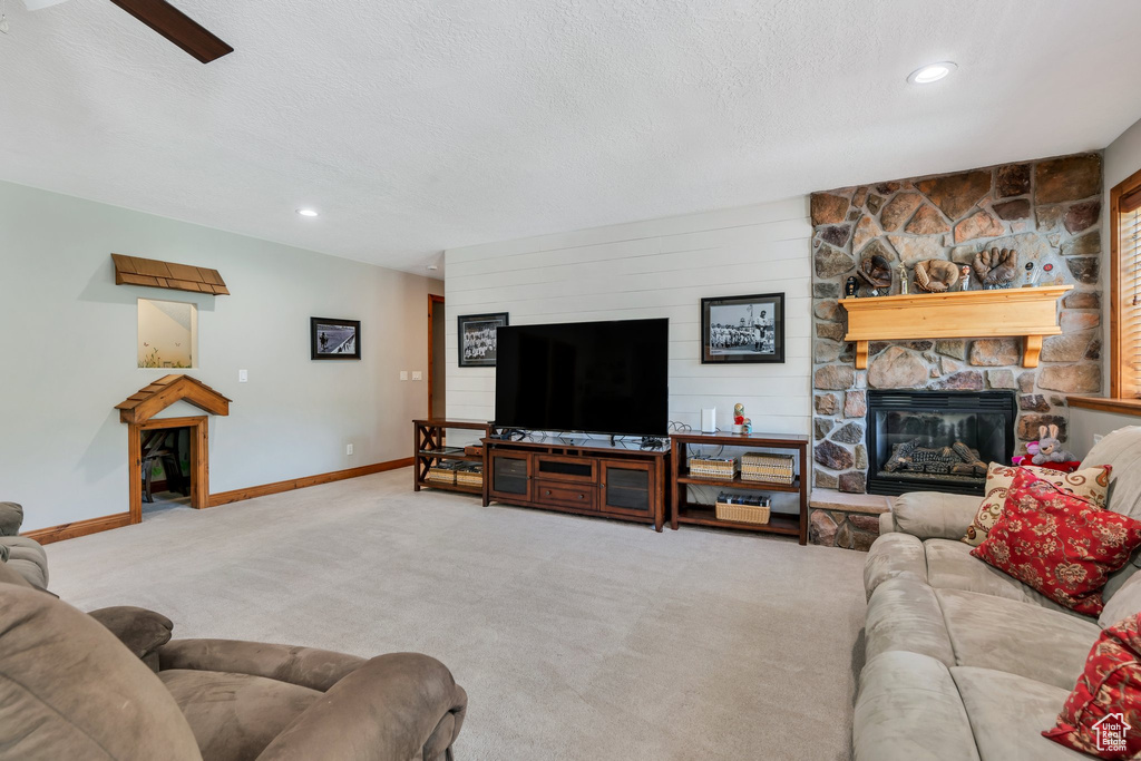 Living area with a fireplace, carpet flooring, baseboards, recessed lighting, and a textured ceiling
