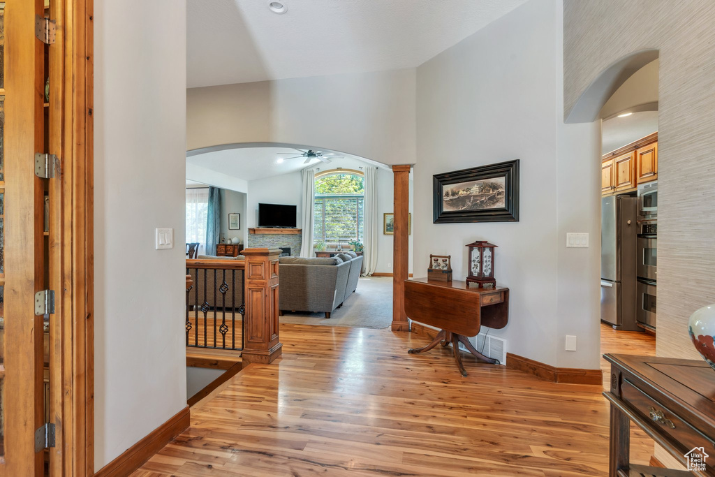 Foyer with arched walkways, a ceiling fan, light wood-style floors, baseboards, and high vaulted ceiling