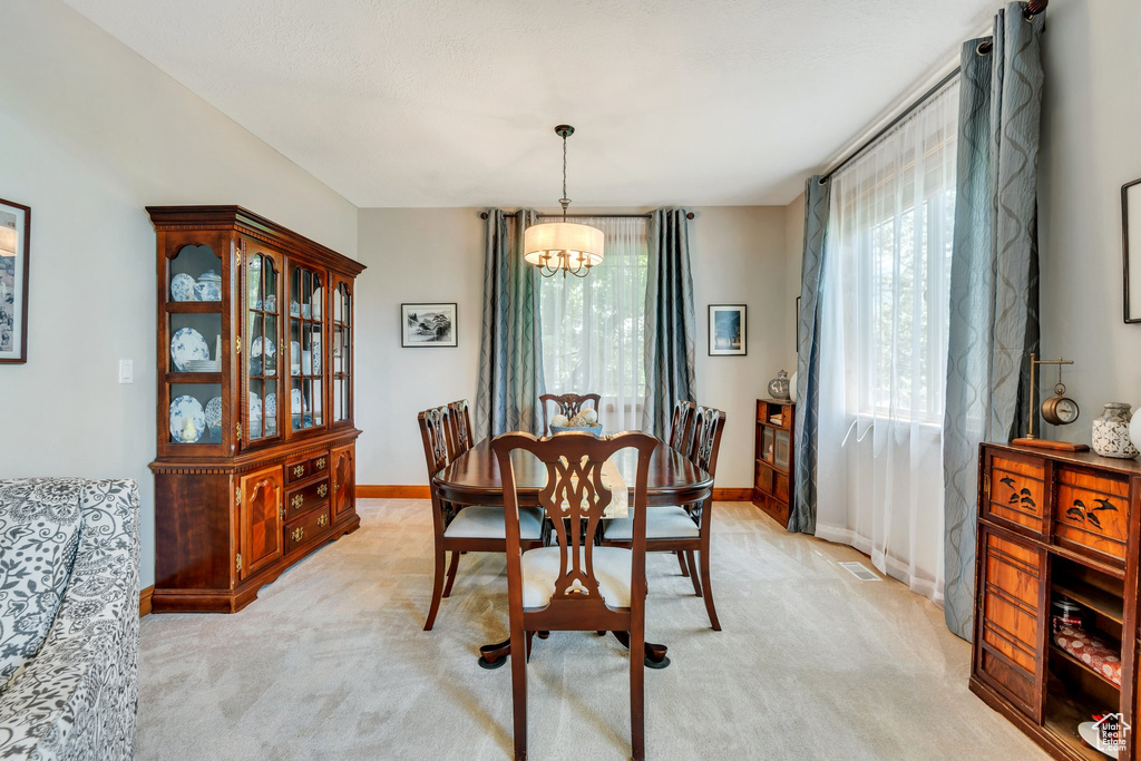 Dining room featuring a chandelier, light colored carpet, and baseboards