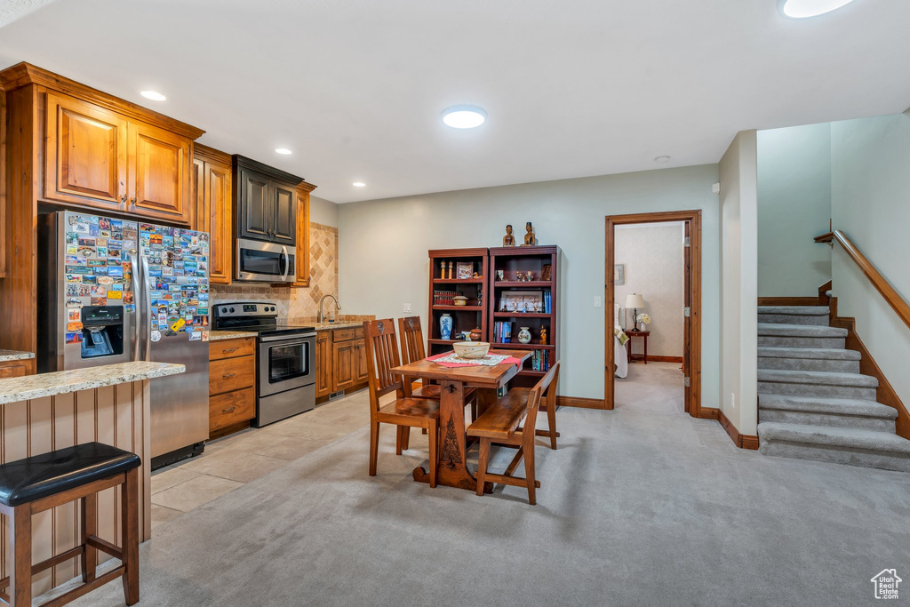 Kitchen featuring stainless steel appliances, decorative backsplash, recessed lighting, baseboards, and brown cabinetry