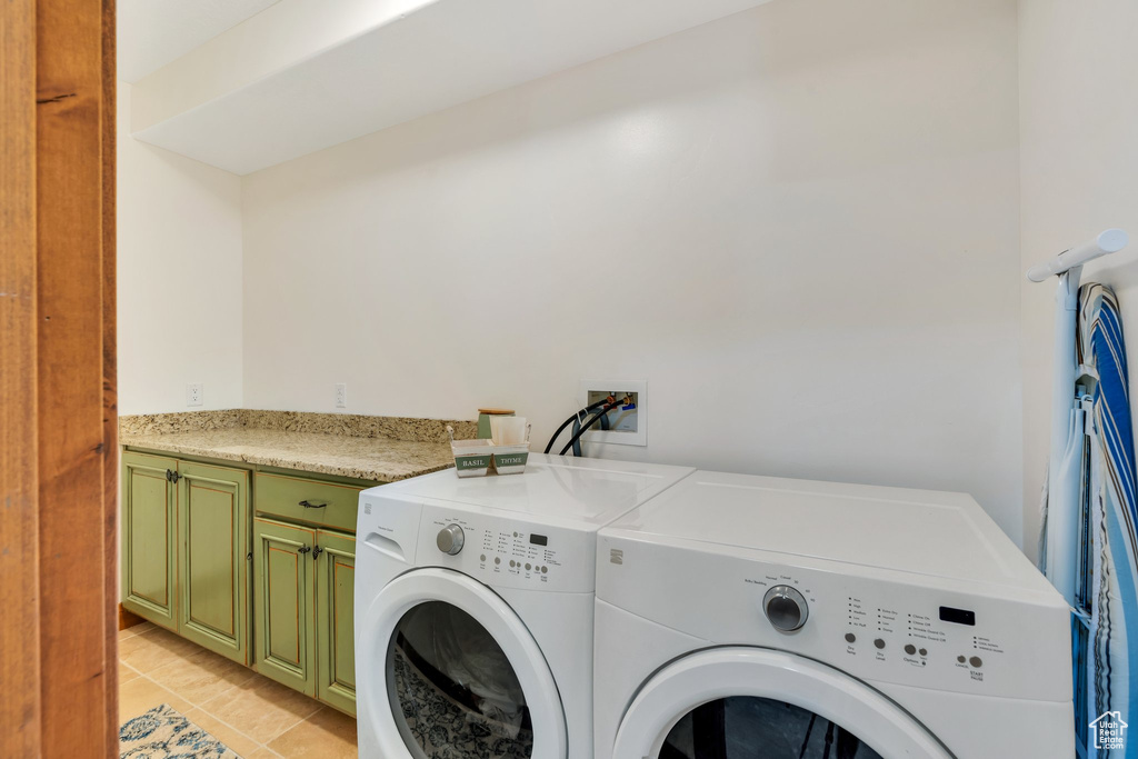 Washroom with washing machine and dryer, cabinet space, and light tile patterned flooring