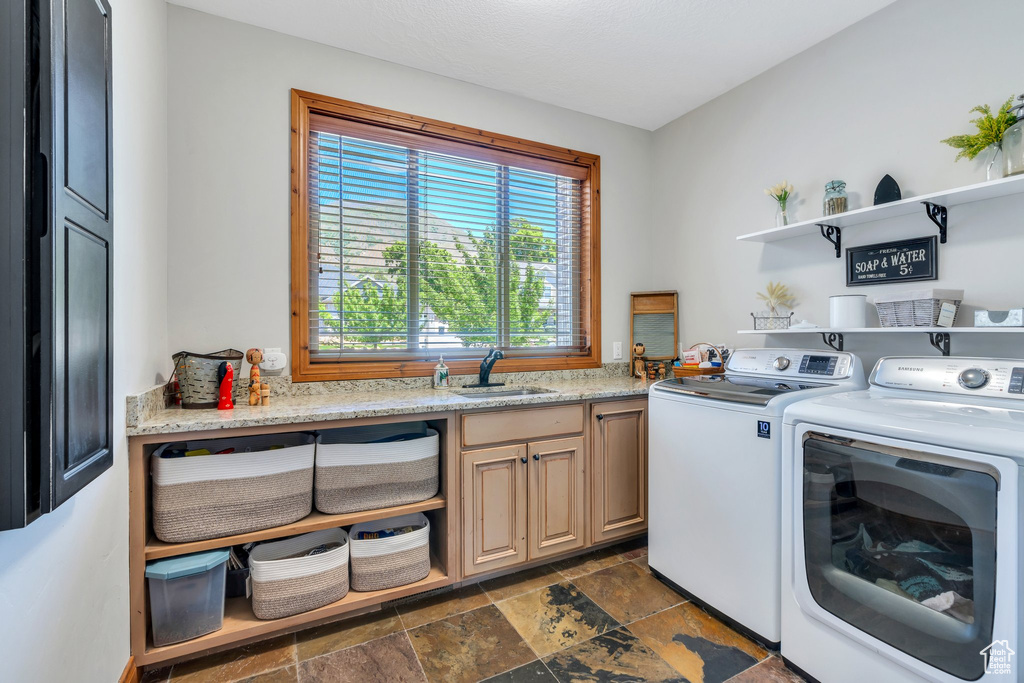 Washroom featuring independent washer and dryer, cabinet space, and dark stone finish floors