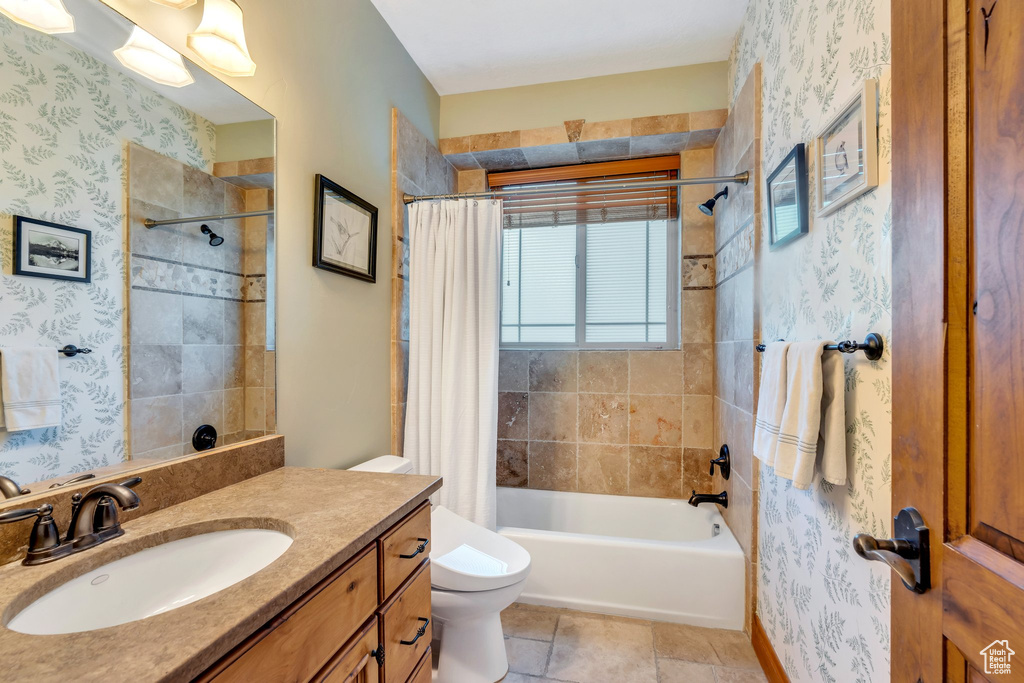 Bathroom with toilet, vanity, shower / bath combo with shower curtain, and wallpapered walls