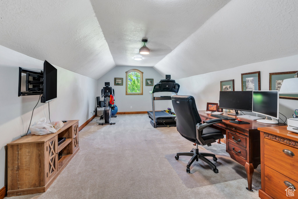 Carpeted home office with a textured ceiling, lofted ceiling, and baseboards