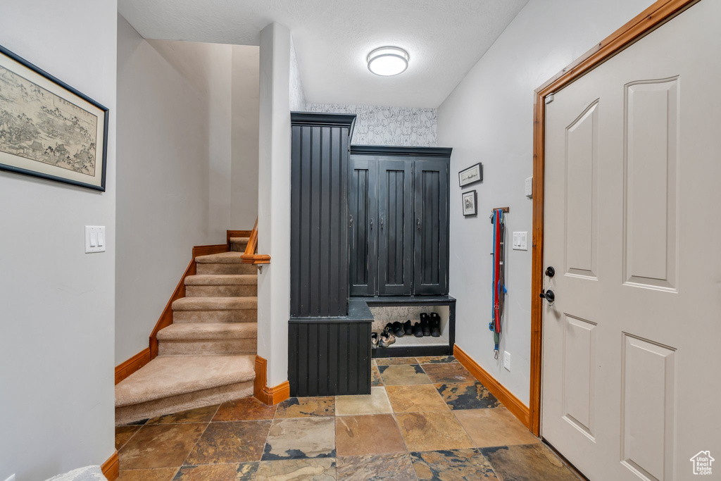 Foyer with baseboards, stone tile floors, and stairs