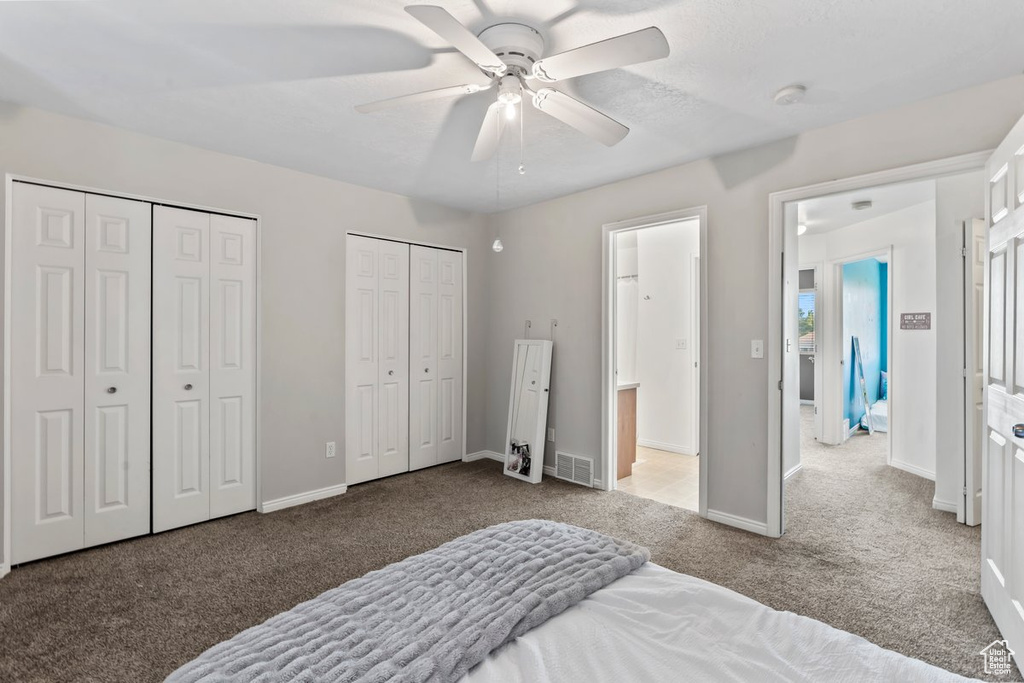 Bedroom with multiple closets, carpet, baseboards, and ceiling fan