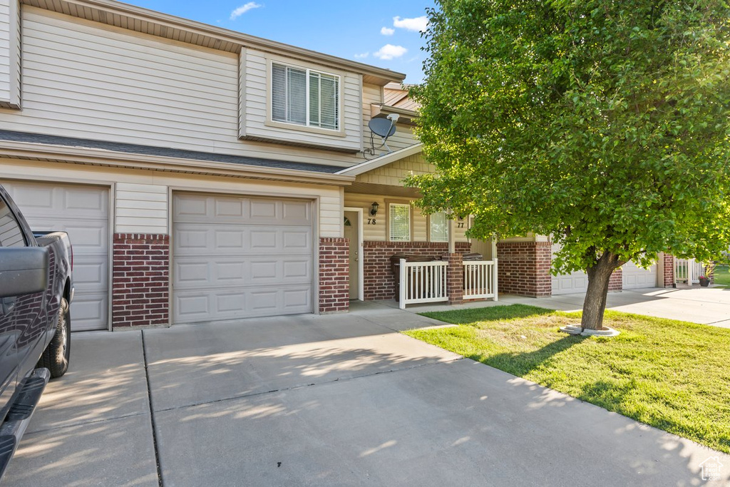 Multi unit property featuring brick siding, concrete driveway, covered porch, and a garage