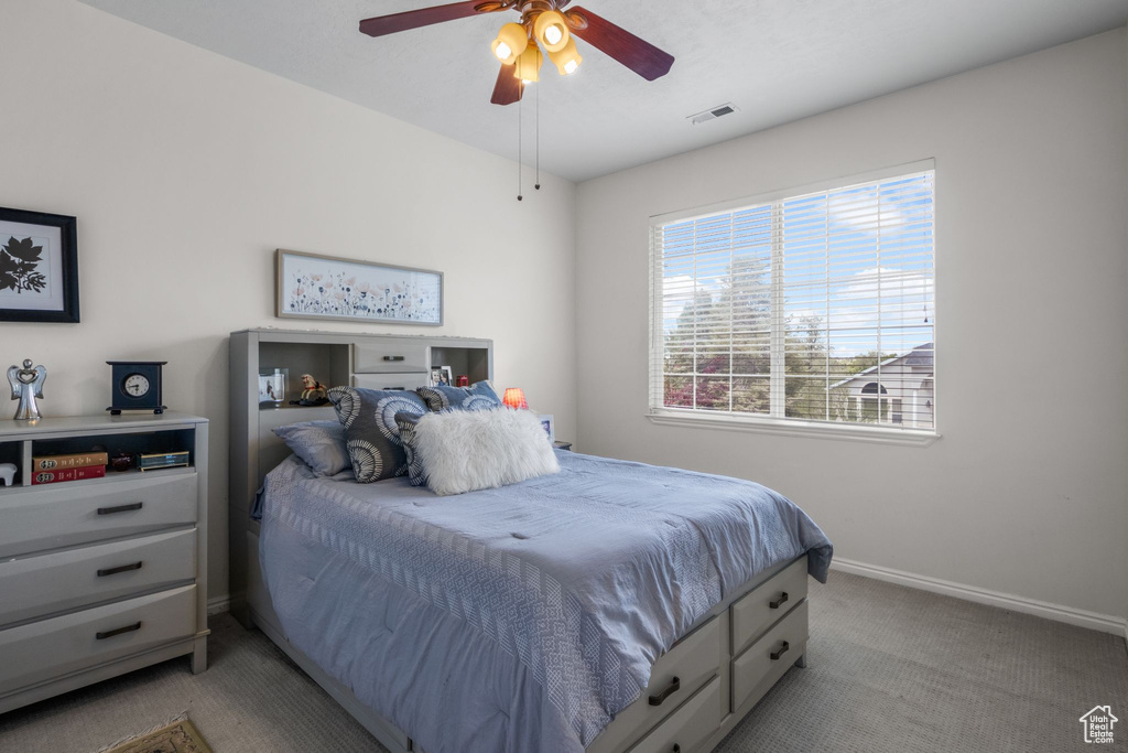 Bedroom featuring light colored carpet, baseboards, and ceiling fan