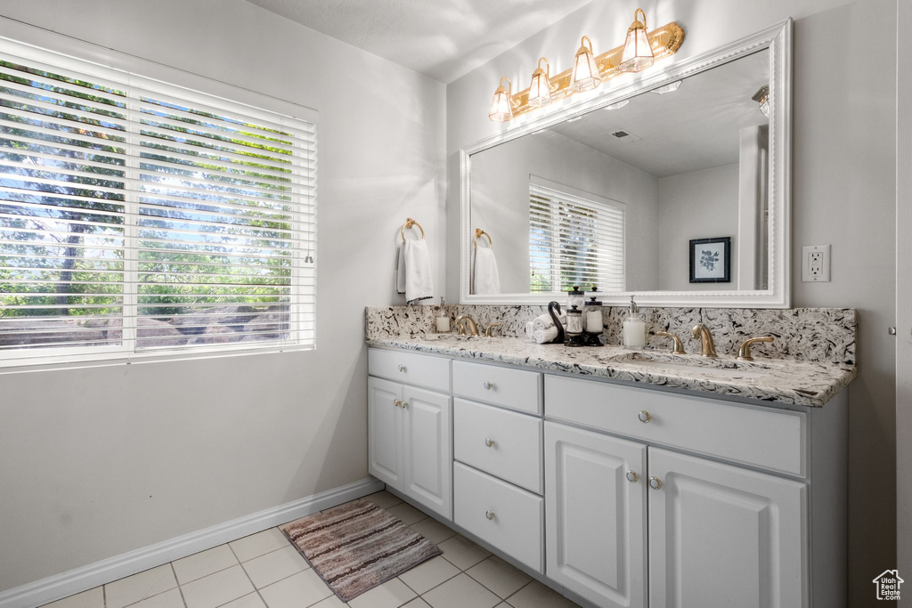 Full bathroom with double vanity, tile patterned floors, and baseboards
