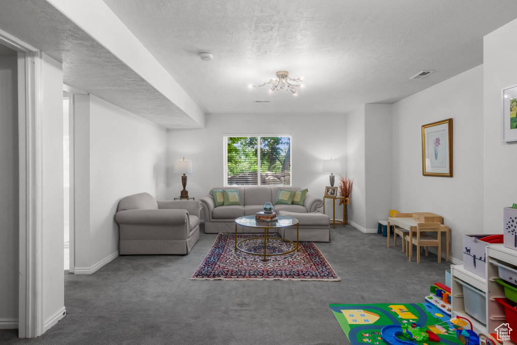 Living area with carpet, baseboards, a textured ceiling, and a chandelier