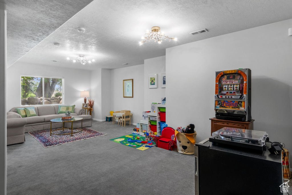 Recreation room featuring a chandelier, carpet flooring, and a textured ceiling