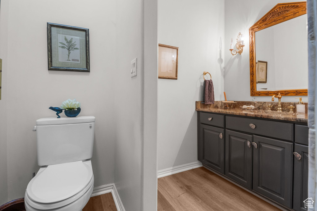 Half bathroom with wood finished floors, vanity, toilet, and baseboards