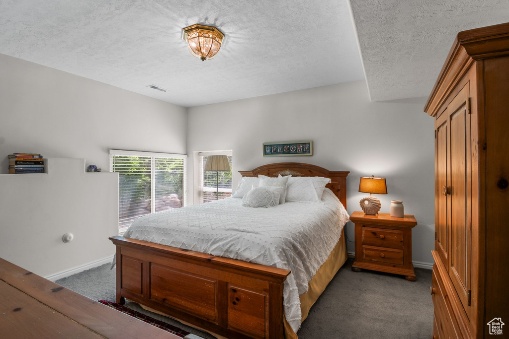 Bedroom with carpet, a textured ceiling, and baseboards