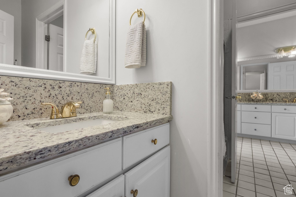 Bathroom featuring tile patterned floors, vanity, and decorative backsplash