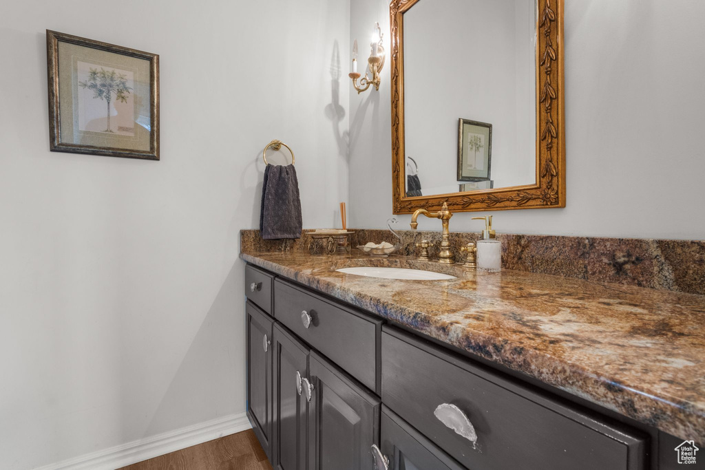Bathroom with vanity, wood finished floors, and baseboards