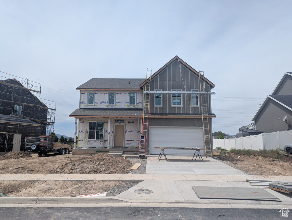 Unfinished property featuring concrete driveway, a porch, board and batten siding, and an attached garage