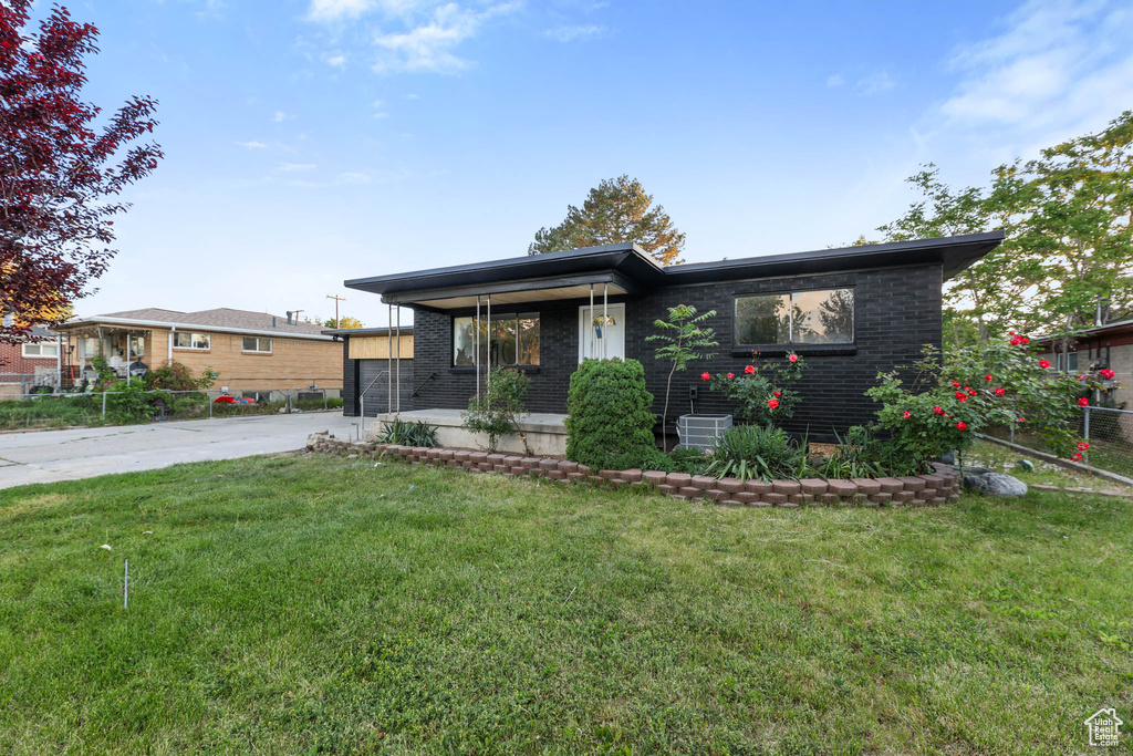 View of front of property with concrete driveway, brick siding, a front lawn, and a porch