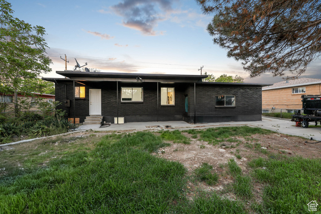View of front facade featuring entry steps, brick siding, and a patio