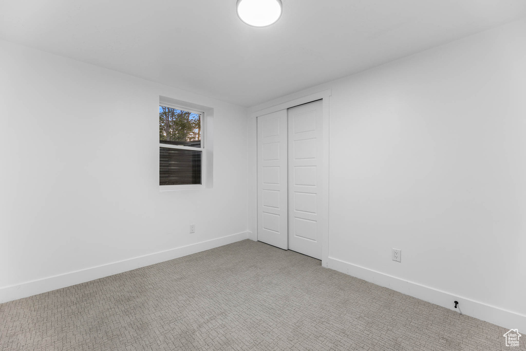 Unfurnished bedroom with light carpet, baseboards, and a closet