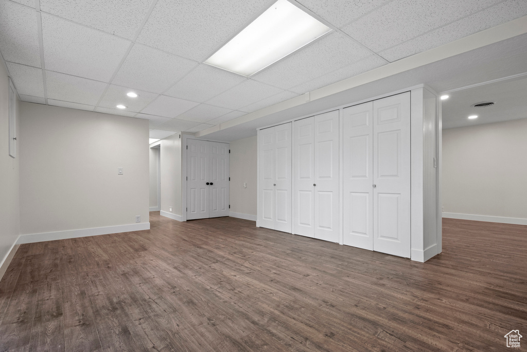 Below grade area with dark wood-type flooring, baseboards, recessed lighting, and a drop ceiling