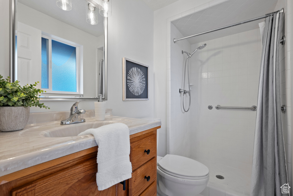 Bathroom featuring vanity, toilet, and a tile shower