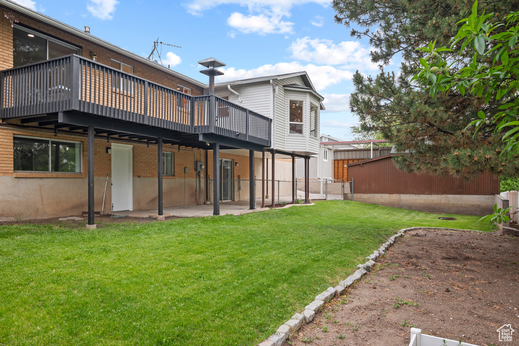 Rear view of house featuring a deck, brick siding, and a patio