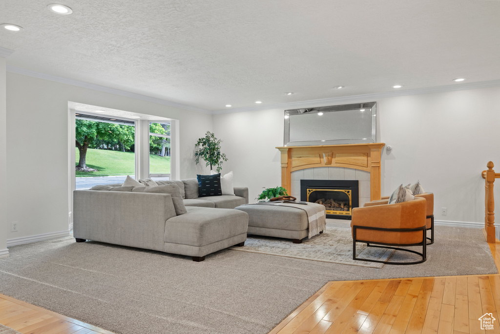 Living area with hardwood / wood-style flooring, crown molding, a tile fireplace, baseboards, and recessed lighting