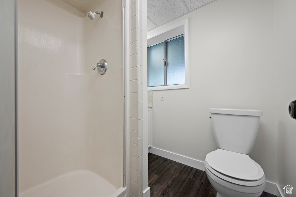 Bathroom featuring baseboards, a shower stall, wood finished floors, and toilet