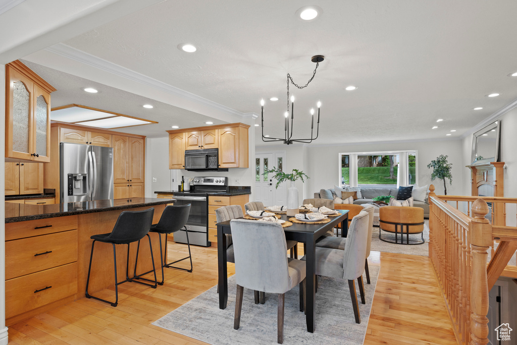 Dining area featuring crown molding, light wood-style flooring, recessed lighting, and a chandelier
