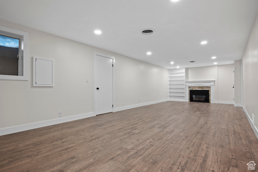 Unfurnished living room featuring wood finished floors, recessed lighting, baseboards, and built in shelves