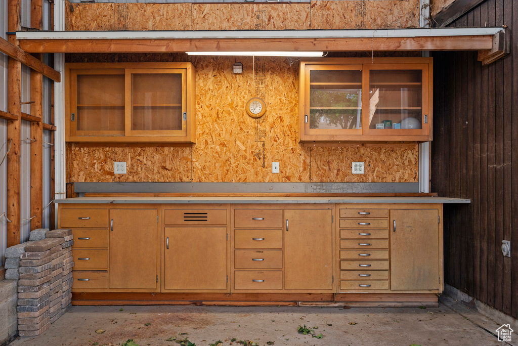 Kitchen featuring glass insert cabinets, unfinished concrete flooring, and light countertops