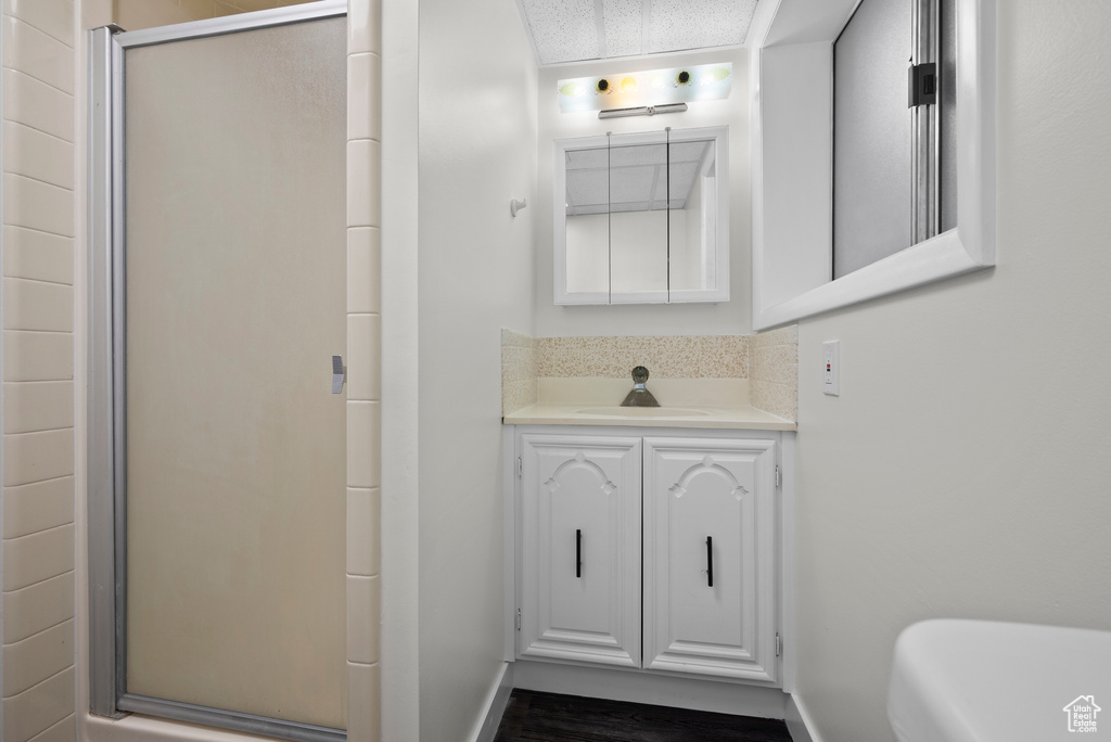 Bathroom featuring a shower stall, vanity, baseboards, and wood finished floors