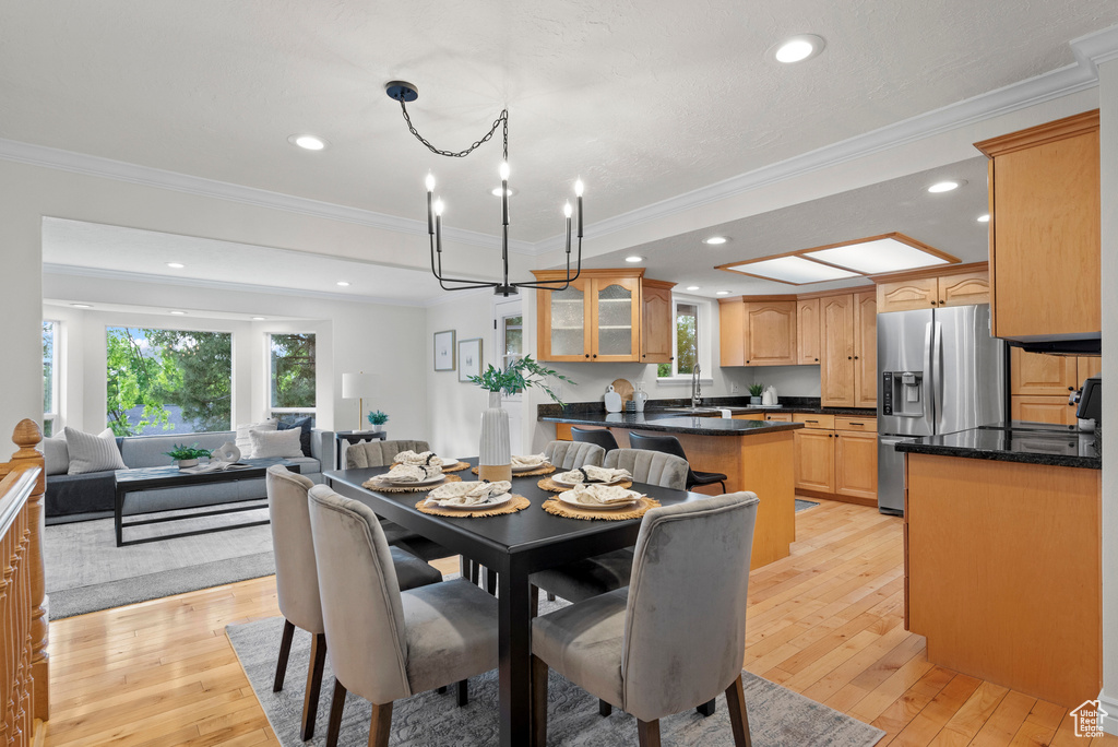 Dining room featuring light wood-style flooring, crown molding, recessed lighting, and a chandelier