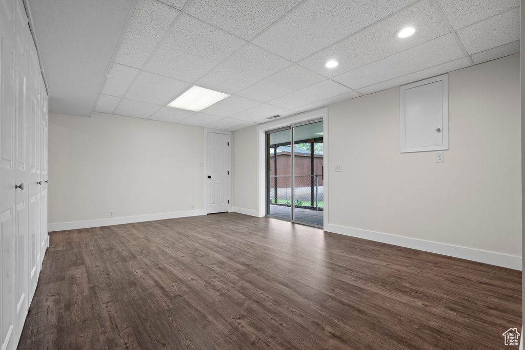 Spare room with dark wood-style floors, a drop ceiling, and baseboards