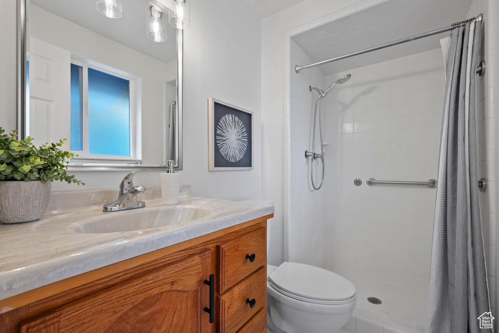 Bathroom with toilet, vanity, and tiled shower