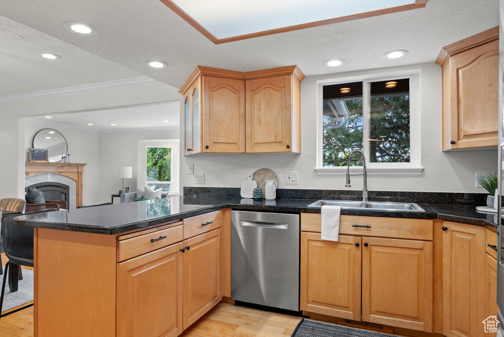 Kitchen with stainless steel dishwasher, a sink, light wood-style floors, a peninsula, and ornamental molding
