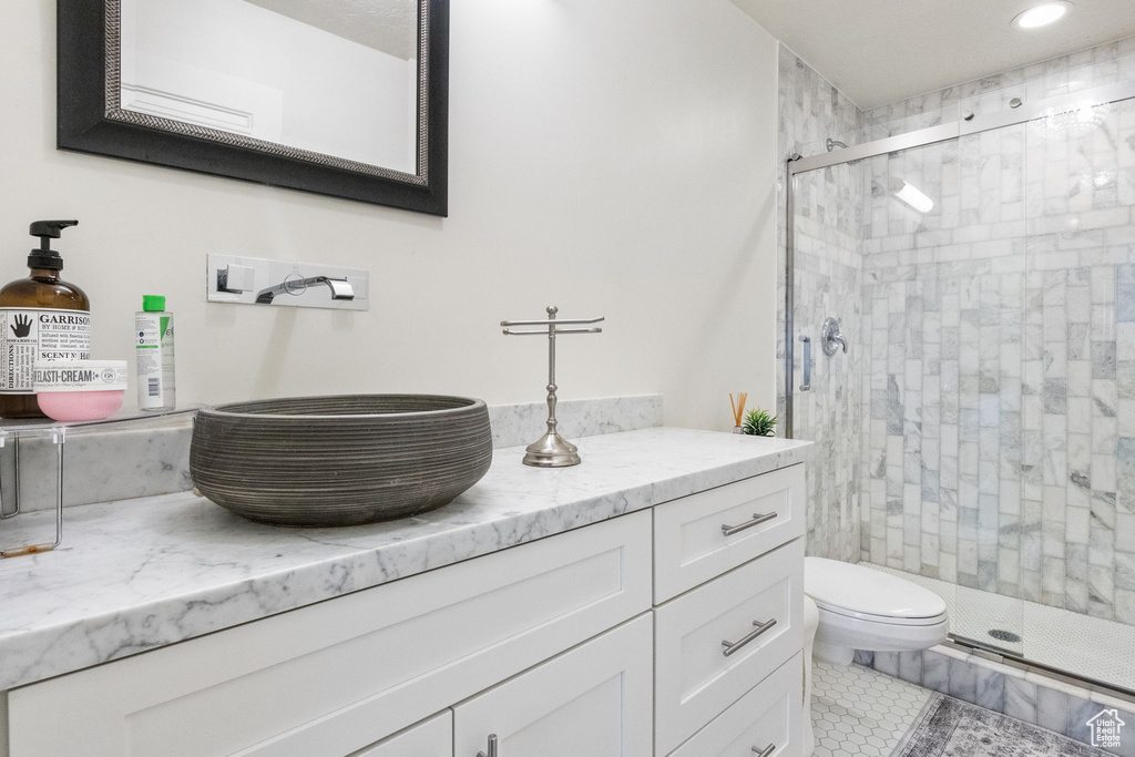 Bathroom with a stall shower, vanity, toilet, tile patterned flooring, and recessed lighting