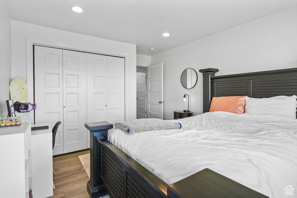 Bedroom with wood finished floors, recessed lighting, and a closet