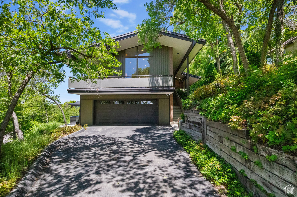 View of front of house featuring driveway, an attached garage, and central air condition unit