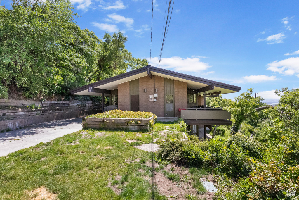 View of front of house featuring brick siding and a balcony