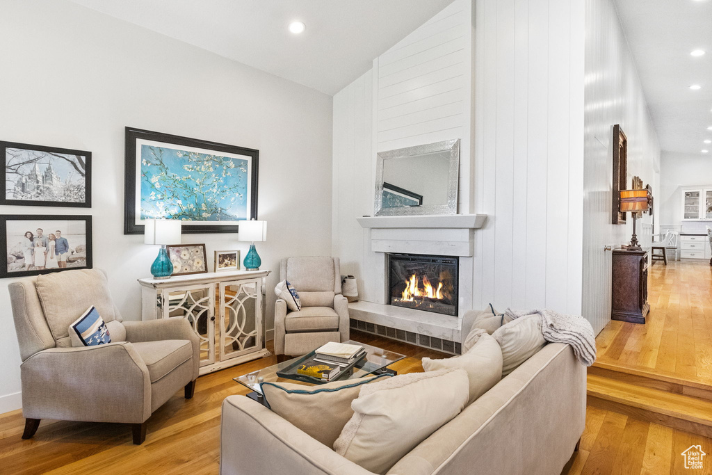 Living room featuring a glass covered fireplace, light wood finished floors, recessed lighting, and vaulted ceiling