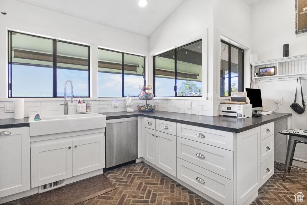 Kitchen with dishwasher, brick floors, dark countertops, tasteful backsplash, and vaulted ceiling