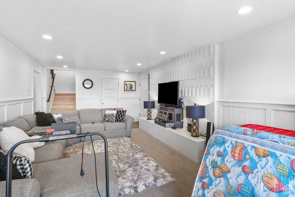 Carpeted living area with recessed lighting, wainscoting, and stairway