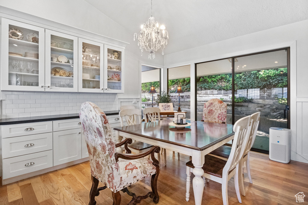 Dining space featuring lofted ceiling, light wood-style floors, and a chandelier