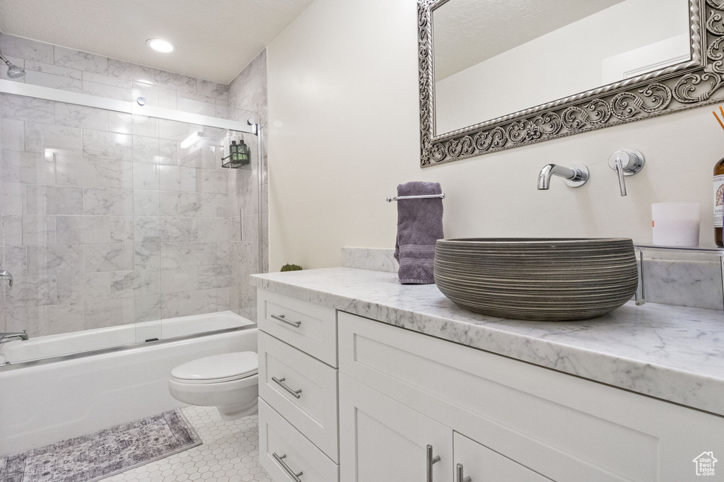 Bathroom with vanity, toilet, enclosed tub / shower combo, tile patterned flooring, and recessed lighting