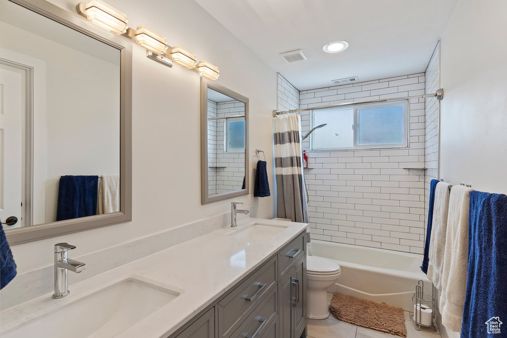 Bathroom featuring double vanity, tile patterned floors, shower / bathtub combination with curtain, toilet, and recessed lighting
