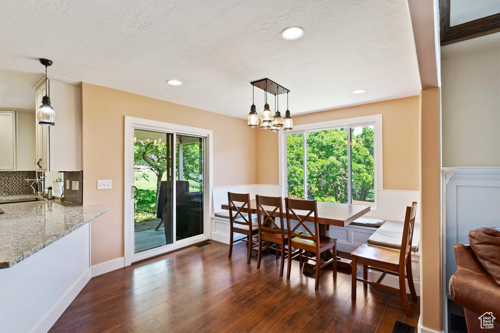 Dining room featuring dark wood finished floors, a wainscoted wall, a textured ceiling, a chandelier, and recessed lighting