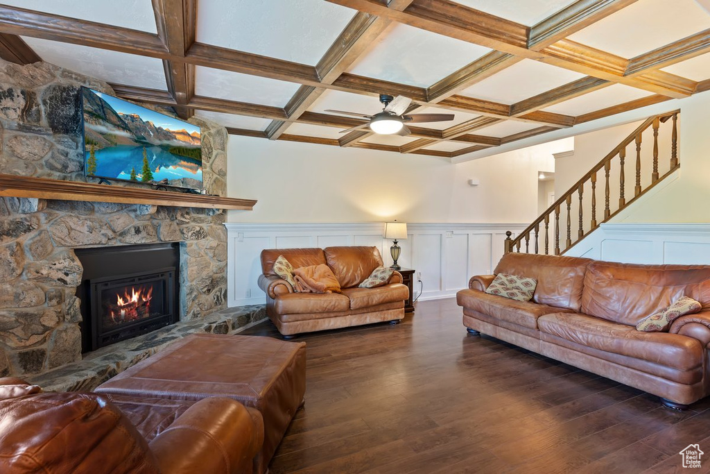 Living room with wood finished floors, a fireplace, beamed ceiling, coffered ceiling, and ceiling fan